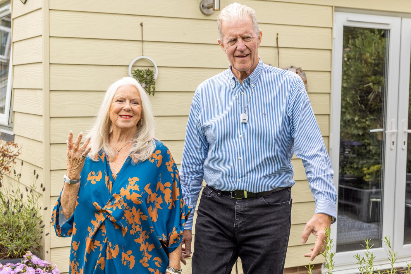 An older couple outside their home, reassured by their Red Button alarm