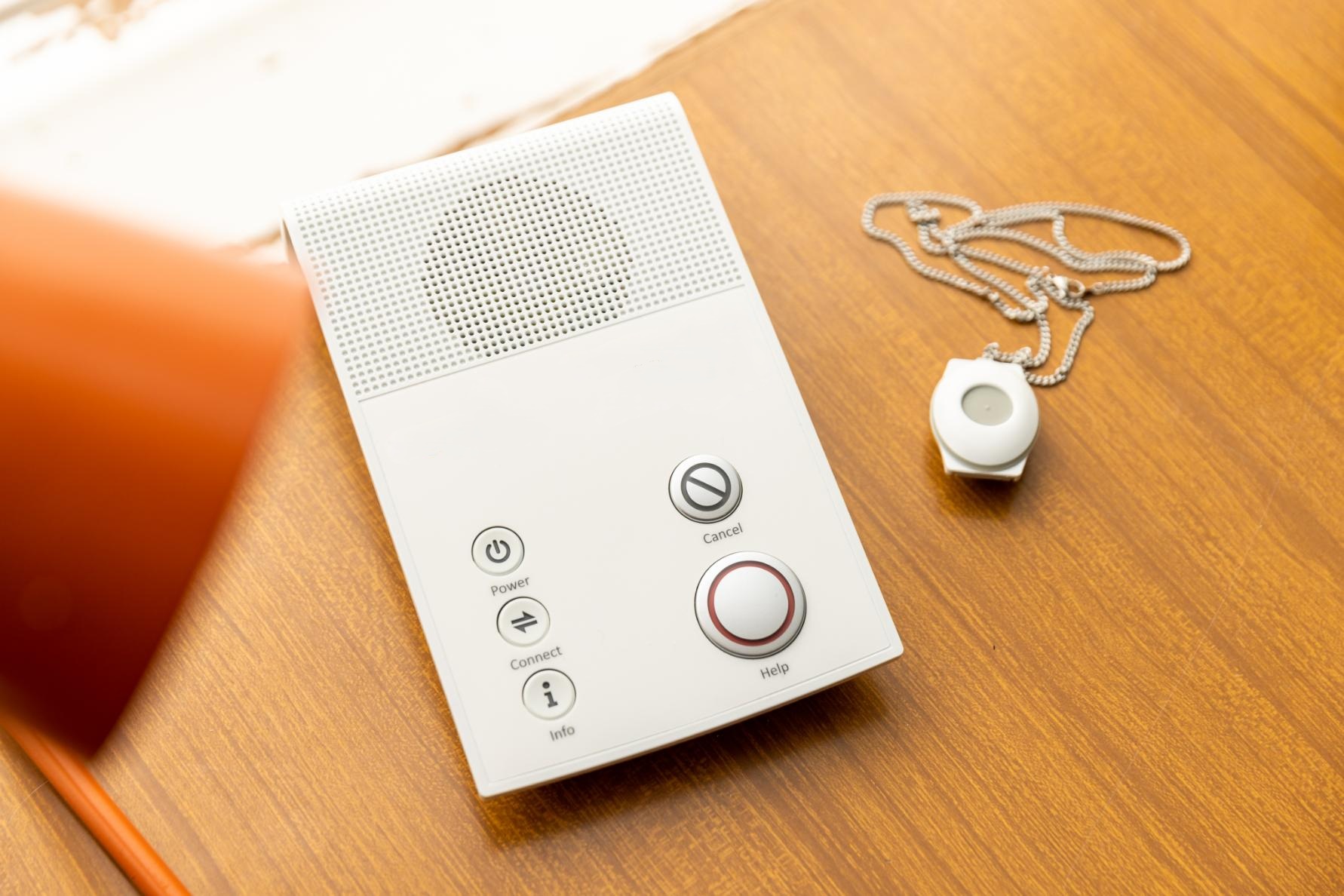 The At Home alarm base unit and pendant on a table